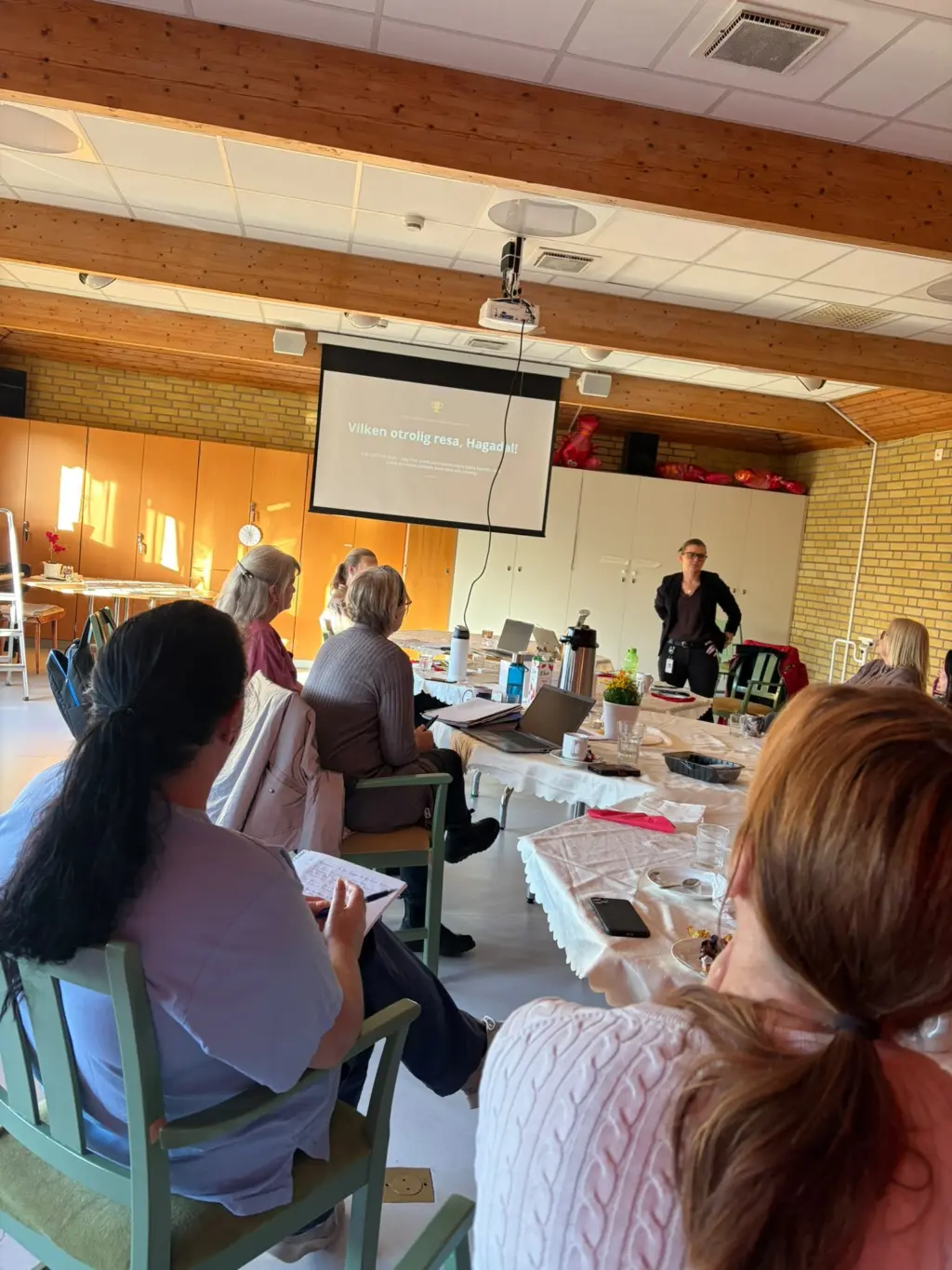 Personer vid ett bord tittar mot en presentation på en skärm.