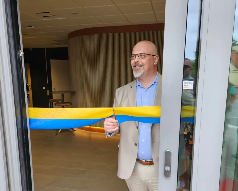 KSO Anders Hansson klipper ett blågult band över ingången till kontaktcenter. Bild tagen utifrån.