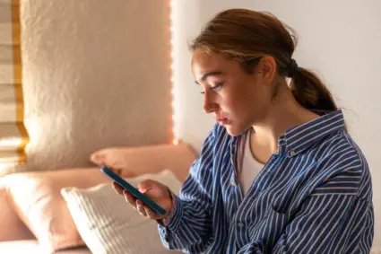 tjej som sitter och tittar på en telefon i handen