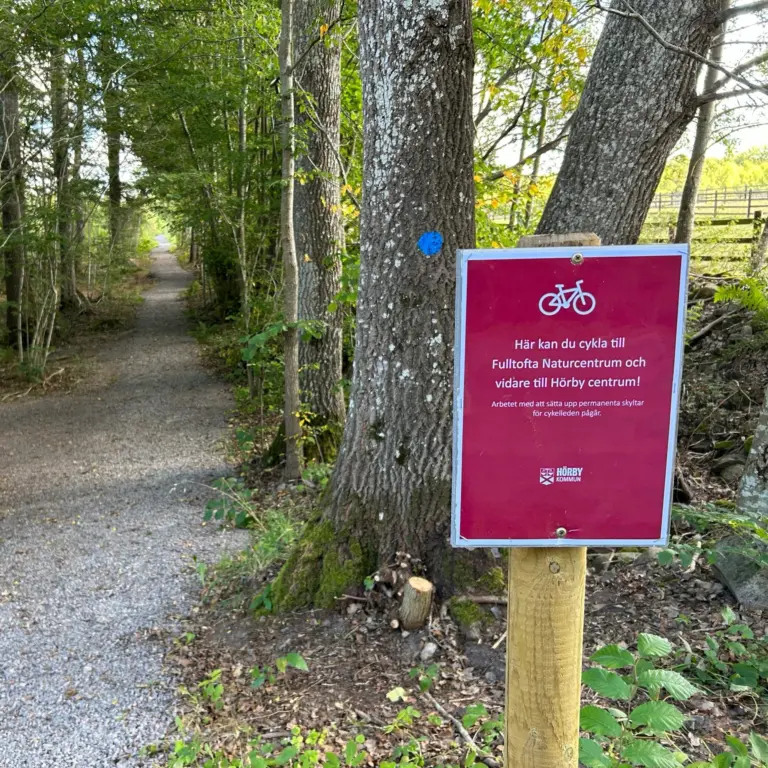 grusad väg kantad av träd, skylt uppmuntrar till cykling