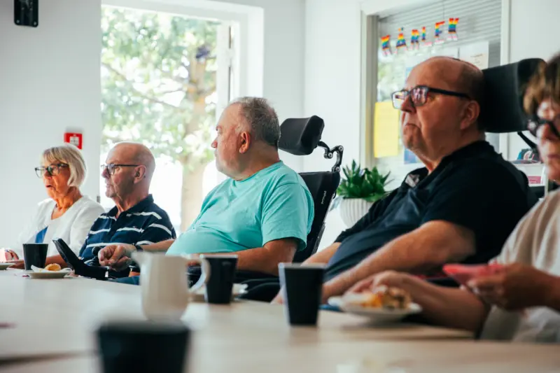 En grupp människor sitter på rad och fikar
