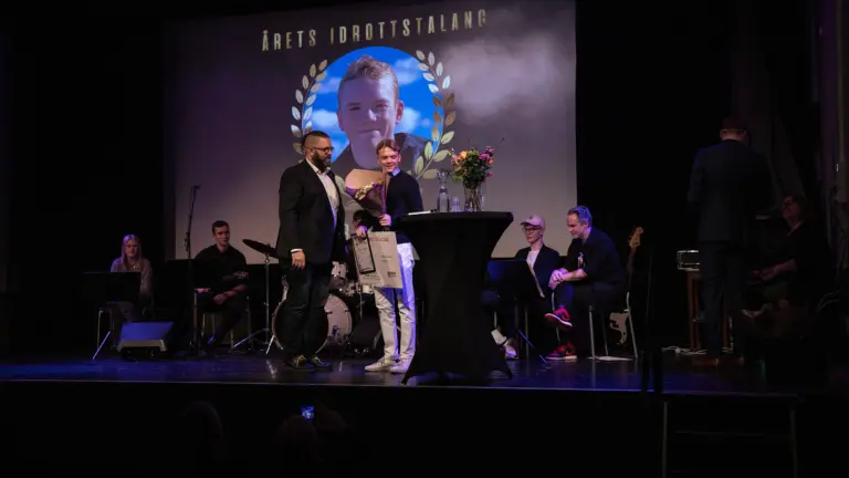 Två personer står på scen och pratar i mikrofon på en prisutdelning