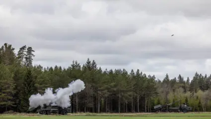 Stridsvagn skjuter på en stor grönyta.