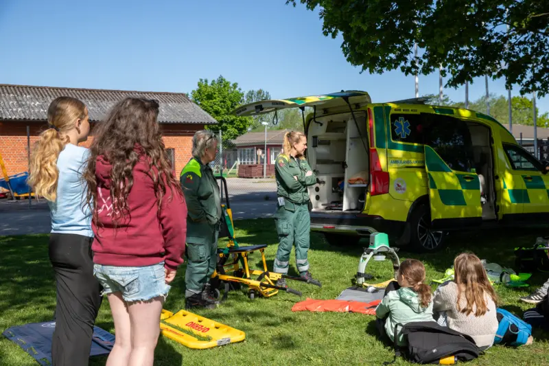 ambulans står parkerad, människor och barn står utanför och pratar