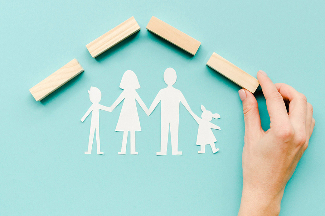 figurer i papper i form av en familj hand som lägger ut klossar som illustrerar ett hem
