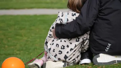 Vuxen håller om barn som håller i en ballong.