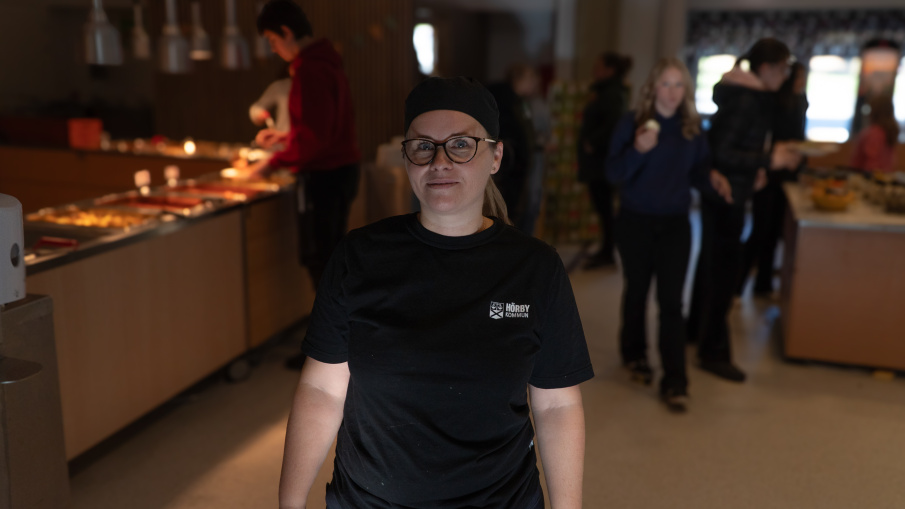 kvinna iklädd arbetskläder för kommunen står i en matsal