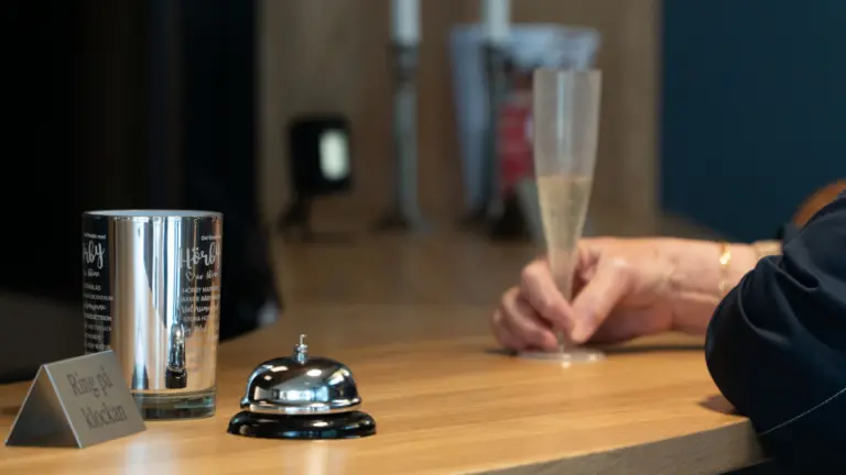 Kvinna håller i ett glas med päroncider vilandes på receptionsdisken
