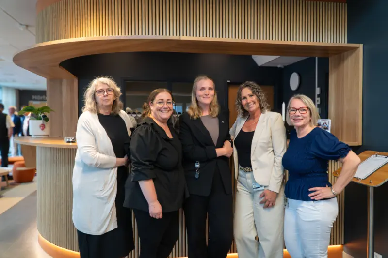 Fem kvinnor står framför den nybyggda receptionen och ler in i kameran.
