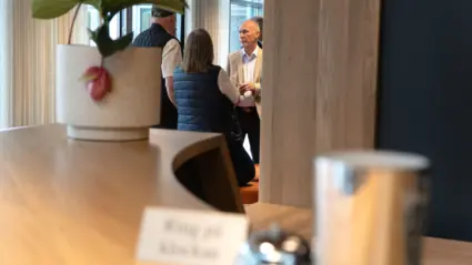 Fokus på en samtalande grupp människor genom receptionsdisken oskarp i förgrunden.