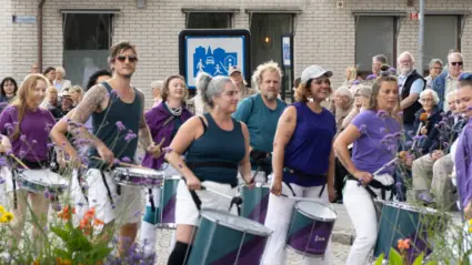 En grupp människor går tillsammans på en gata och spelar trummor.