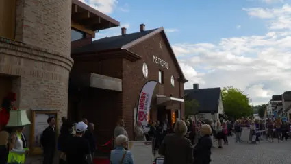 En stor folksamling har samlats på en gata utanför en tegelbyggnad.