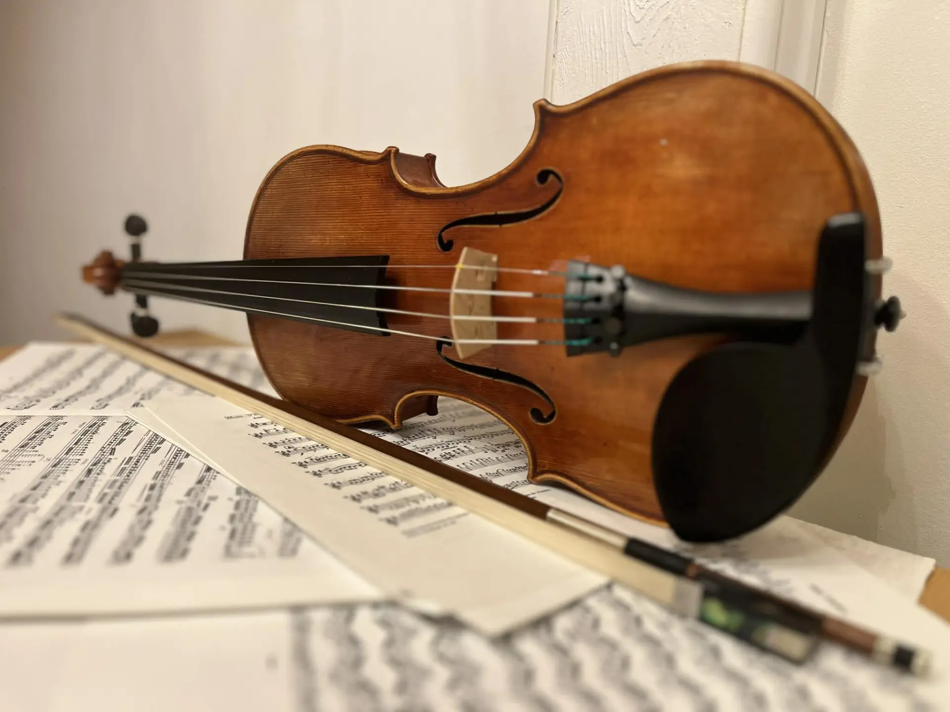 Cello med stråke liggandes på ett golv täckt av noter