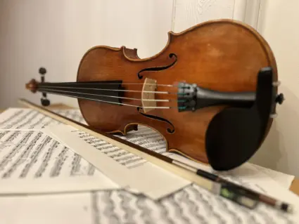 Cello med stråke liggandes på ett golv täckt av noter