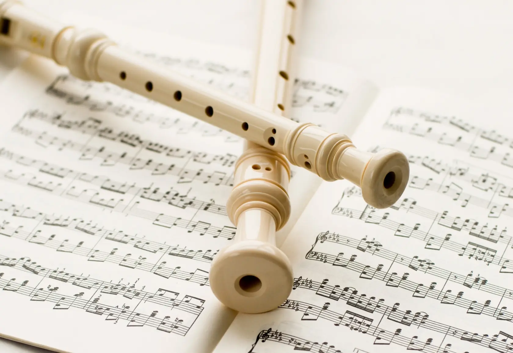 två blockflöjtar ligger korsade över ett notblad