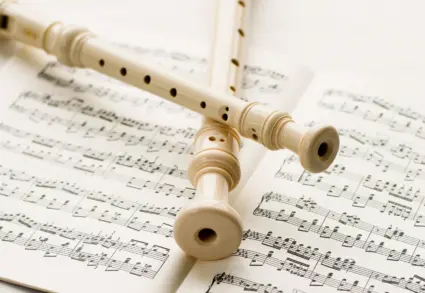 två blockflöjtar ligger korsade över ett notblad