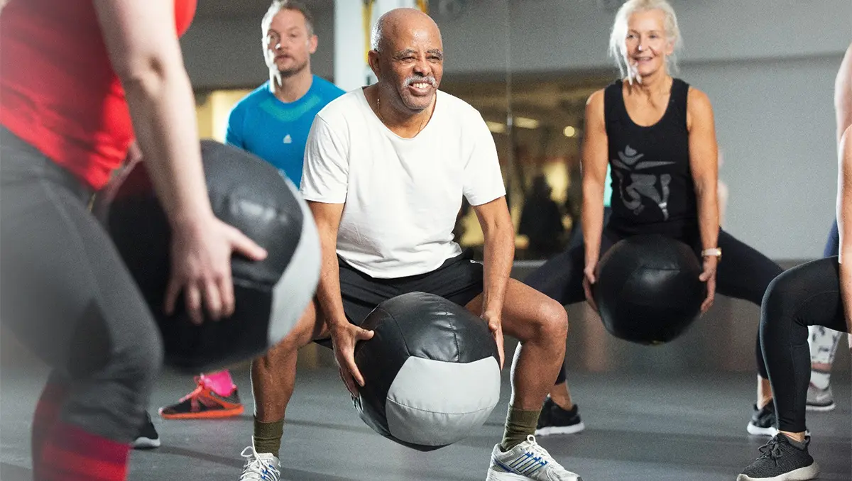 Pensionärer tränar i grupp med stor boll.