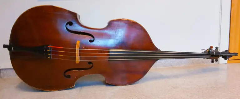 Kontrabas som ligger på sidan framför en vit vägg