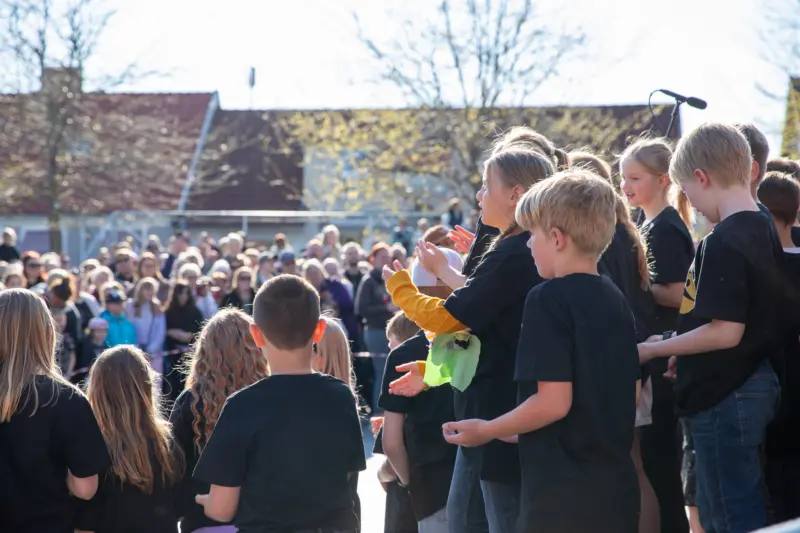 En stor barnk&ouml;r &auml;r mitt i s&aring;ngen framf&ouml;r en glad publik.