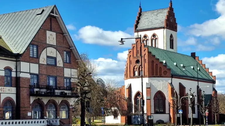 kyrka och stor husbyggnad vid en väg som går förbi ett torg