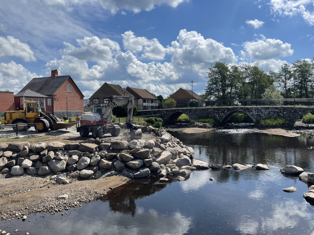traktoch och grävmaskin på ett en byggplats vid ett vattendrag