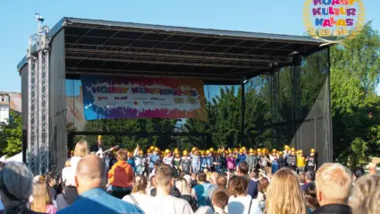 flera människor har samlats framför en scen där barn står med guldhattar.