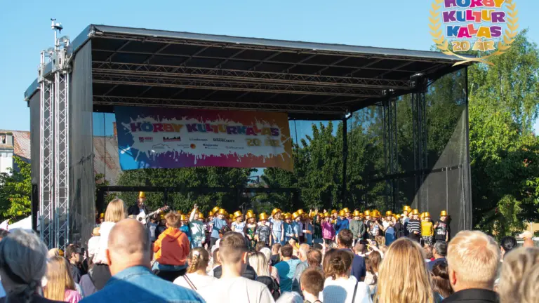 flera människor har samlats framför en scen där barn står med guldhattar.