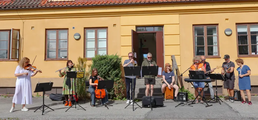 Hörby kulturskola, lärare med instrument poserar framför en gul byggnad