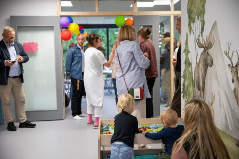 Många människor samlade i en lokal. Små barn leker med leksaker.