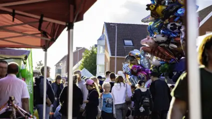 Folkvimmel under marknaden, med marknadsstånd på båda sidorna, vinkel från under ett stånds tak.