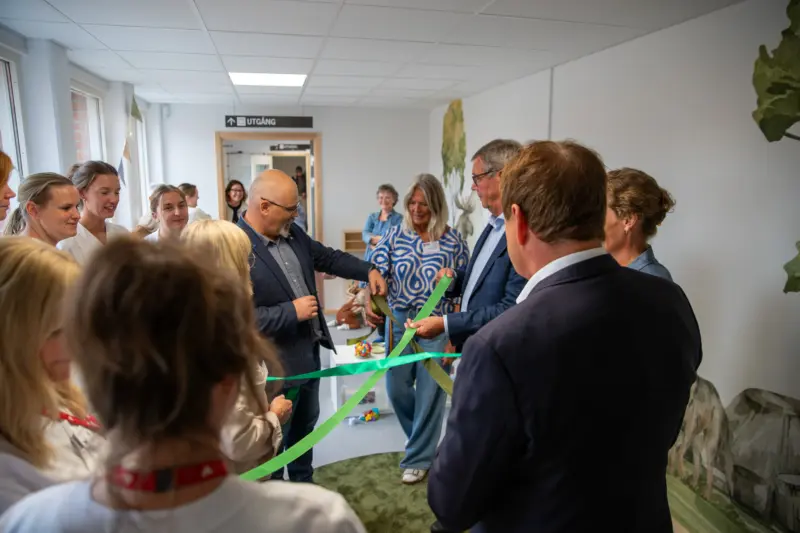 M&auml;nniskor i grupp som st&aring;r och knyter ihop gr&ouml;na band.