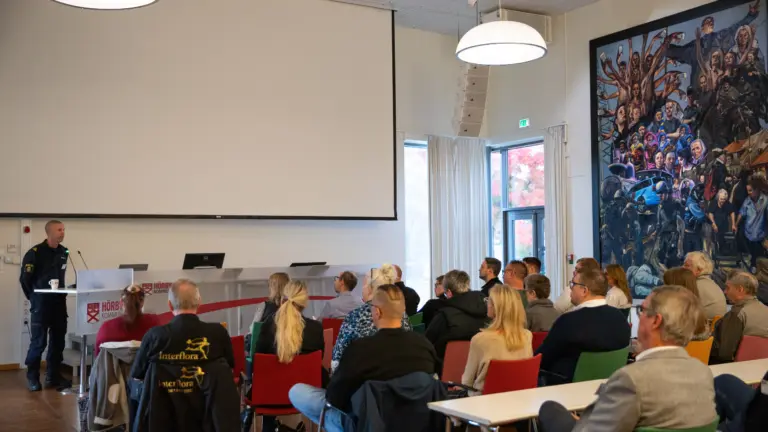 man i uniform som står vid ett podium och pratar med åhörare