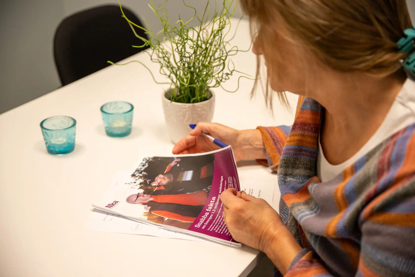 Kvinna sitter vid ett bord böjd över papper med penna i handen