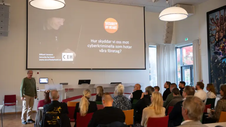 Människa som står och föreläser inför en grupp med människor
