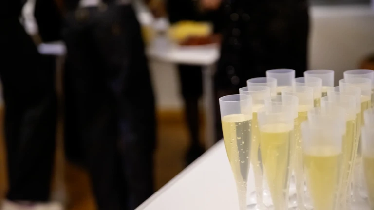 Närbild på rader av plastglas med ljus cider i