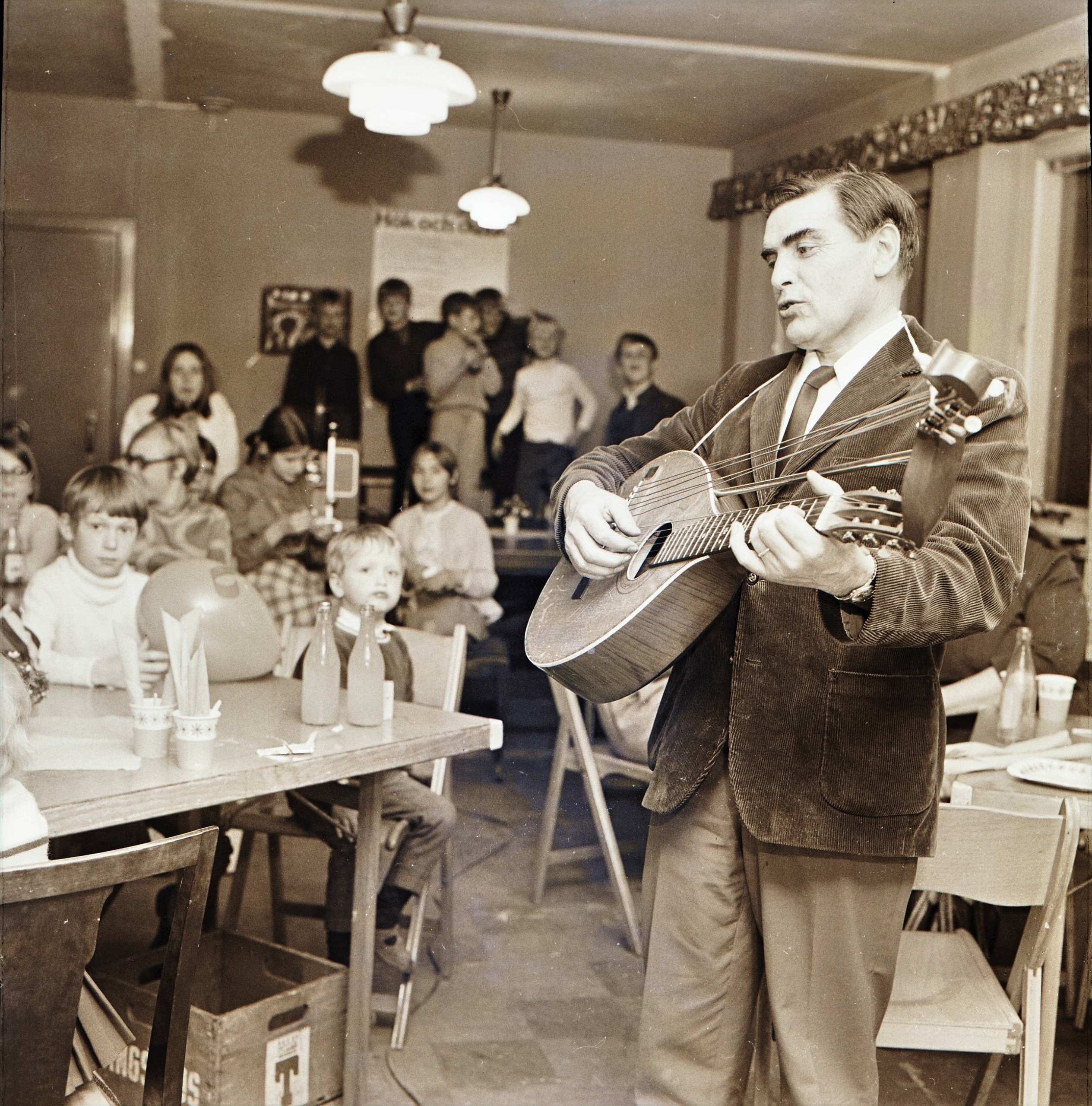 Erik Myrgren, medelålders herre, spelar banjo för några barn. Åldrad bild tagen på 60-talet