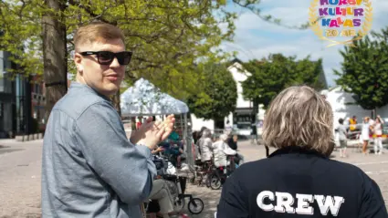 två personer står på ett torg varav den ena är vänd mot kameran. På den andres tröja står det "Crew".
