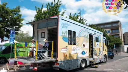 en stor buss som är omgjord till att innehålla en massa böcker står placerad på ett torg.