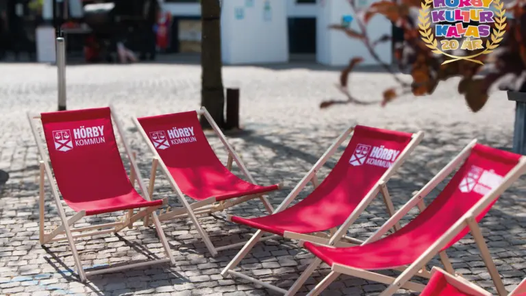 fem röda strandstolar med en logga där det står Hörby kommun på.