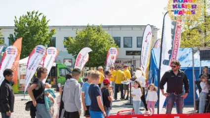 flera ungdomar och barn står i kö på ett torg med festival