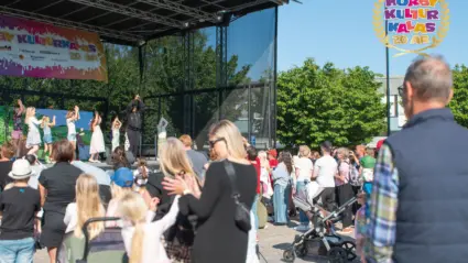 Flera människor står framför en scen, barn står på scenenen.