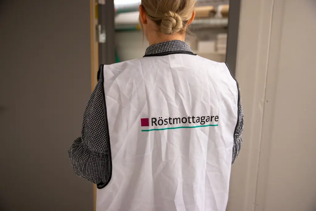 ryggtavla på en person som bär en väst med röstmottagare.