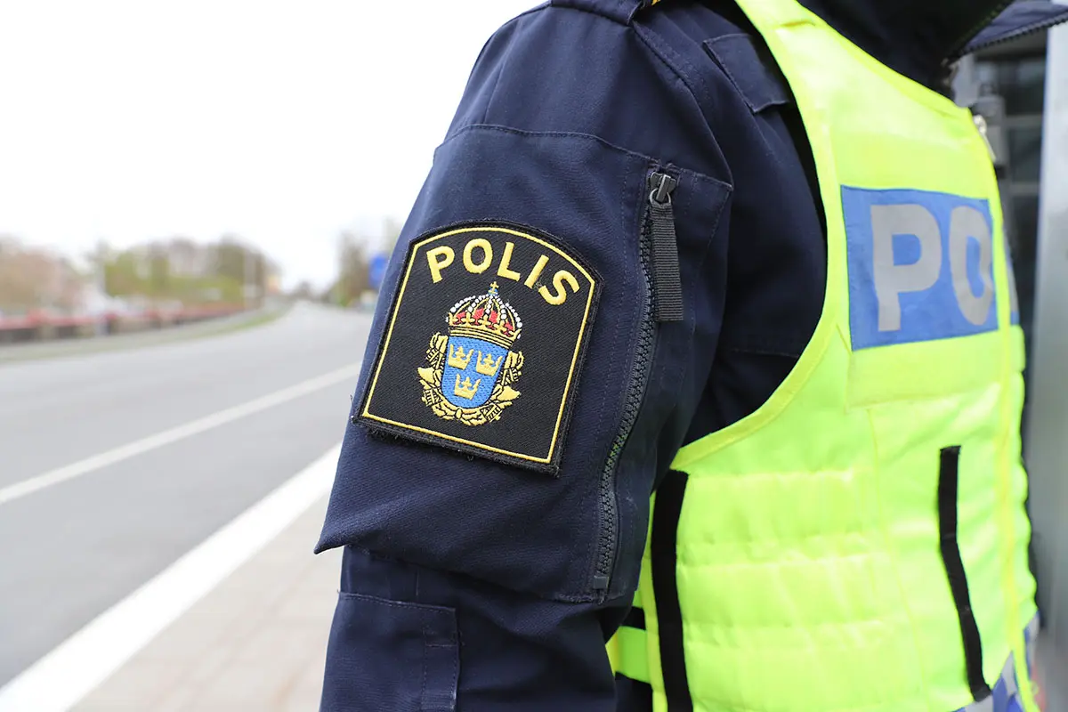 Halvbild på polisuniformerad person med polisemblem i fokus.
