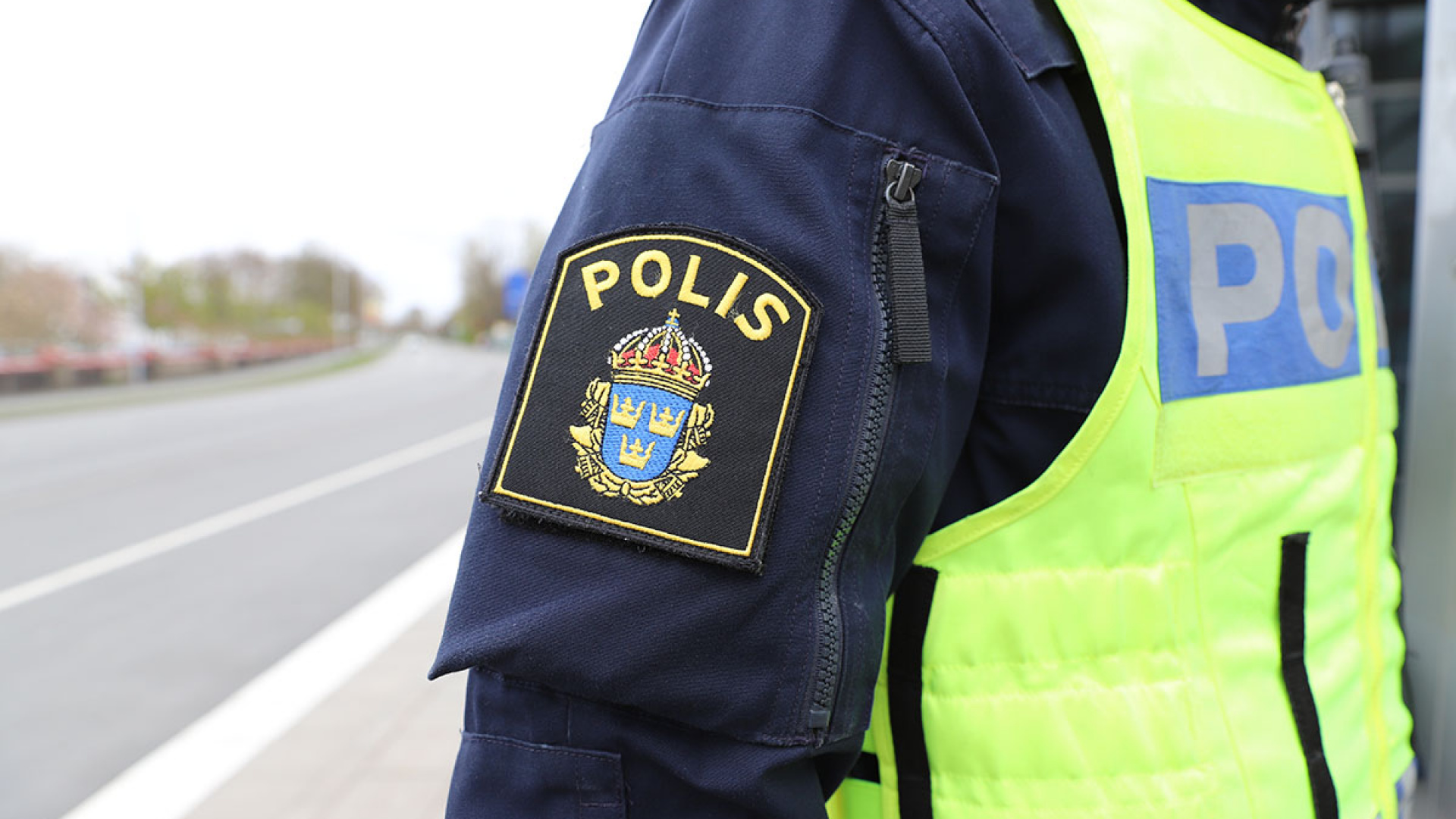 Halvbild på polisuniformerad person med polisemblem i fokus.