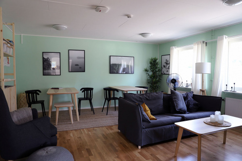 Gemensamhetsrum med soffgrupp, bord och stolar och mintgröna väggar.