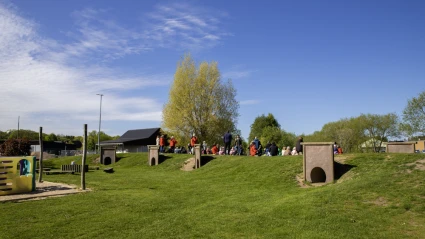 Vuxna och barn sitter i en backe på en skolgård