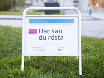 Skylt som står på gräsmatta, budskapet på skylten lyder "Här kan du rösta"