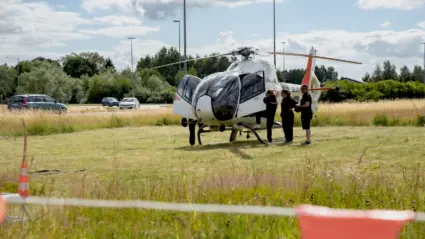 Fält med helikopter i närheten av bilväg