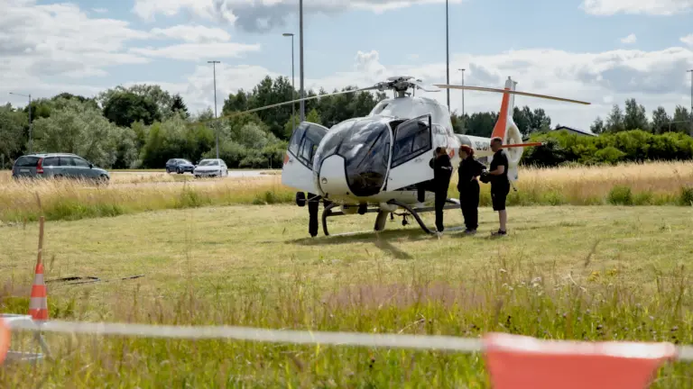 Fält med helikopter i närheten av bilväg