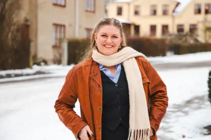 Kvinna står utomhus, det är snö bakom henne